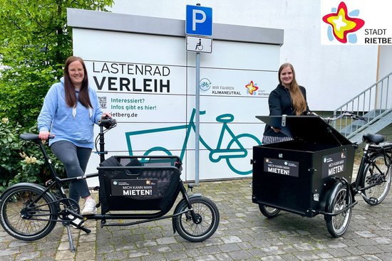 Zwei Frauen stehen mit zwei Lastenfahrrädern vor einer Garage in schauen in die Kamera.