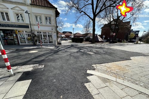 Das Foto zeigt die provisorisch asphaltierte Straße. Es ist gutes Wetter, die Sonne scheint.
