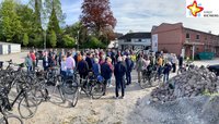 Dutzende Radler stehen inmitten ihrer Fahrräder im Hinterhof der Rosen-Apotheke in Neuenkirchen und lauschen einem Vortrag.