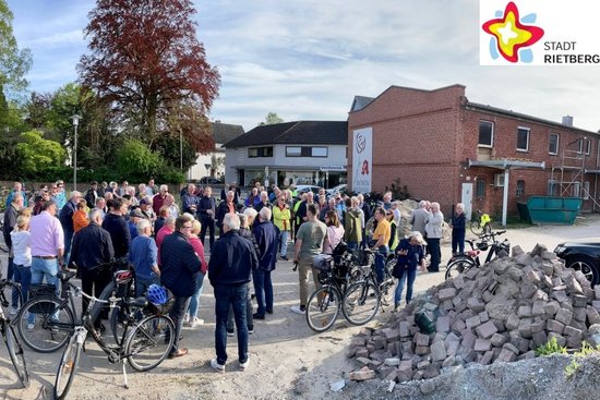 Dutzende Radler stehen inmitten ihrer Fahrräder im Hinterhof der Rosen-Apotheke in Neuenkirchen und lauschen einem Vortrag.