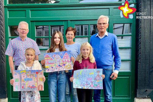 Drei Erwachsene und drei Kinder mit selbstgemalten Bildern in den Händen stehen nebeneinander vor einer grünen Tür.