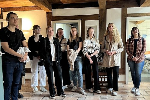 Junge Frauen und Männer stehen nebeneinander vor einer Fachwerkwand.