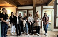 Junge Frauen und Männer stehen nebeneinander vor einer Fachwerkwand.
