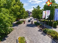 Zu sehen ist eine Luftaufnahme von einem Teil der Rathausstraße im Bereich Nordtor. man sieht in der Mitte die Straße, links Bäume und rechts Fahnen.
