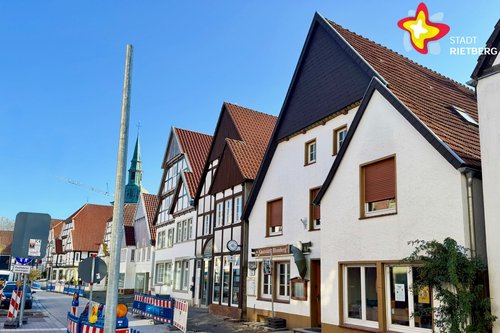 Das Bild zeigt das Haus von außen. Der Himmel ist blau. Auf der Straße stehen Absperrungen wegen der Sanierung der Rathausstraße.