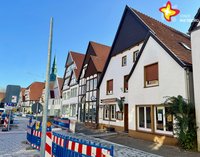 Das Bild zeigt das Haus von außen. Der Himmel ist blau. Auf der Straße stehen Absperrungen wegen der Sanierung der Rathausstraße.