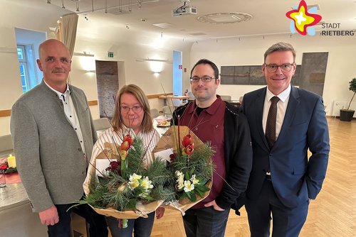 Die genannten Personen stehen im Ratssaal und schauen in die Kamera. Die Geehrten halten jeweils einen Blumenstrauß in den Händen.