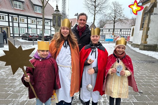 Die genannten Mädchen sind als Heilige Drei Könige verkleidet. Ein Mädchen hält einen Stern in der Hand. Alle schauen in die Kamera.