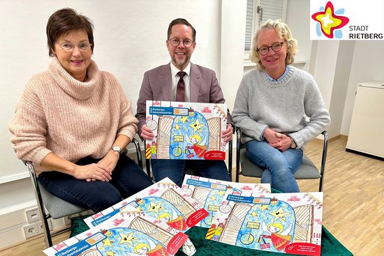 Doris Vogel, Markus Oldendorf und Anja Rodenbeck sitzen nebeneinander auf drei Stühlen - vor sich eine grün bedeckte Kiste, auf der mehrere farbige Adventskalender liegen.