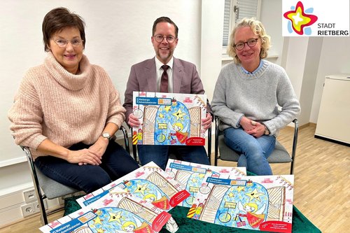 Doris Vogel, Markus Oldendorf und Anja Rodenbeck sitzen nebeneinander auf drei Stühlen - vor sich eine grün bedeckte Kiste, auf der mehrere farbige Adventskalender liegen.