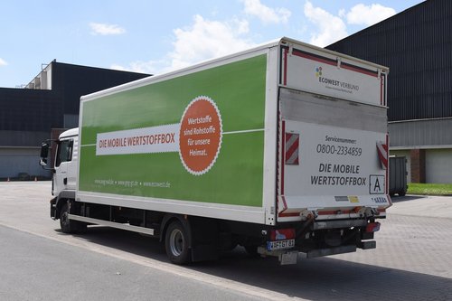 Ein Lastwagen mit bunter Aufschrift ist von hinten zu sehen.