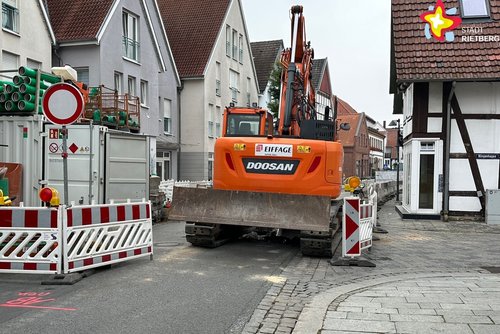 Blick auf die Baustelle in der Rathausstraße. Ein Bagger und Sperrschilder sind zu sehen.