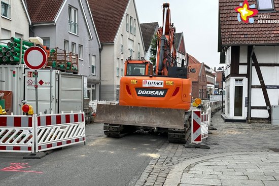 Blick auf die Baustelle in der Rathausstraße. Ein Bagger und Sperrschilder sind zu sehen.