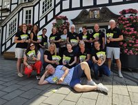 kulturig-Vertreter und Partner vor dem Rathaus. Sie zeigen das neue Programmheft in die Kamera. Michael Beckhoff, Initiator des Cultura Rock Festivals, liegt quer vor seinen Mitstreitern auf dem Boden.
