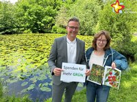 Die genannten Personen stehen vor einem Teich im Klostergarten. Er ist bedeckt mit vielen Seerosen. Rundherum stehen grüne Bäume.