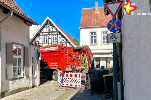 In einer Straßeneinfahrt steht ein großer roter Lkw und versperrt die Durchfahrt.