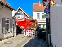 In einer Straßeneinfahrt steht ein großer roter Lkw und versperrt die Durchfahrt.