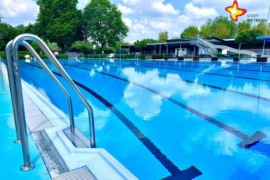 Das Bild zeigt ein menschenleeres Schwimmbecken mit schwarzen Linien auf dem blauen Beckenboden.