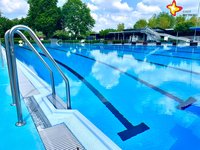 Das Bild zeigt ein menschenleeres Schwimmbecken mit schwarzen Linien auf dem blauen Beckenboden.