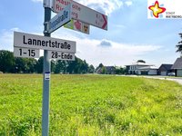 Eine Straßenschild mit der Aufschrift Lannerstraße ist vor einer grünen Wiese zu sehen.