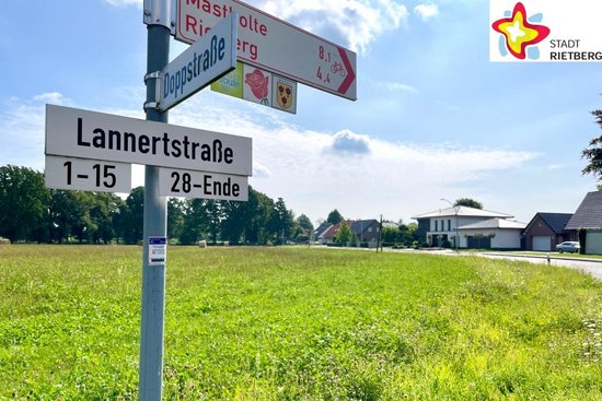 Eine Straßenschild mit der Aufschrift Lannerstraße ist vor einer grünen Wiese zu sehen.