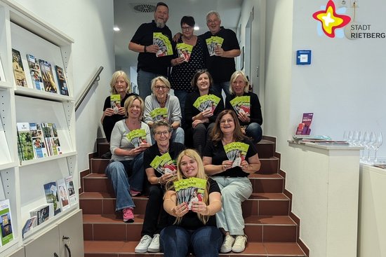 Die kulturig-Vertreter sitzen auf einer Treppe bzw. stehen dahinter und zeigen das neue Spielzeit-Heft in die Kamera.