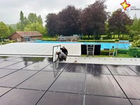 Man sieht, wie die Module installiert werden. Im Hintergrund ist das Schwimmbecken zu sehen.