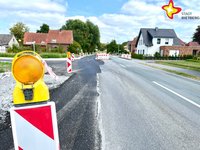 An der Straße Langer Schemm ist links eine neu asphaltierte Abbiegespur mit Absperrbaken flankiert.