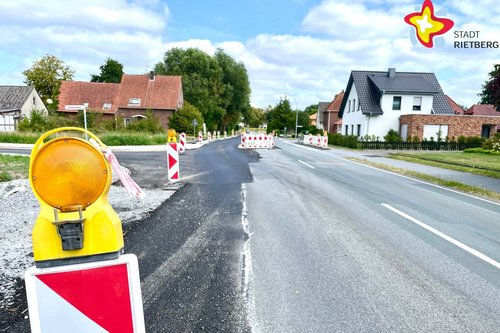An der Straße Langer Schemm ist links eine neu asphaltierte Abbiegespur mit Absperrbaken flankiert.