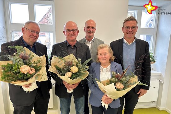 Die zu Ehrenden und der Bürgermeister sowie der Personalratsvorsitzende stehen im Besprechungsraum vor dem Fenster nebeneinander und schauen in die Kamera. Die Geehrten halten Blumensträuße in den Händen.